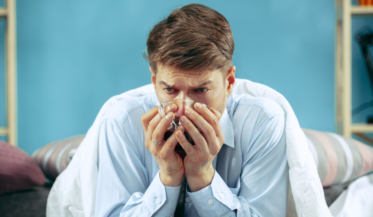 Hombre preocupado sosteniendo una taza, mostrando signos de bronquitis que podrían requerir atención médica y seguimiento a domicilio